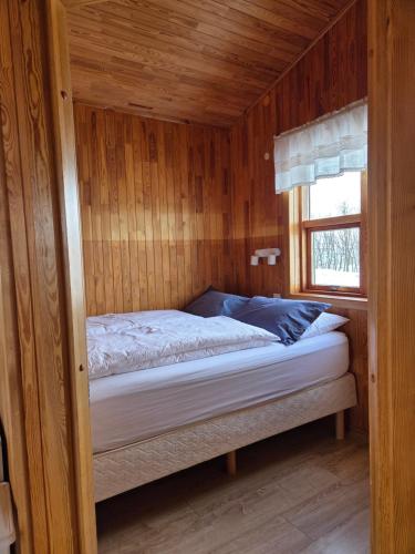 a bed in a wooden room with a window at Ekra Cottages in Lagarfljótsvirkjun