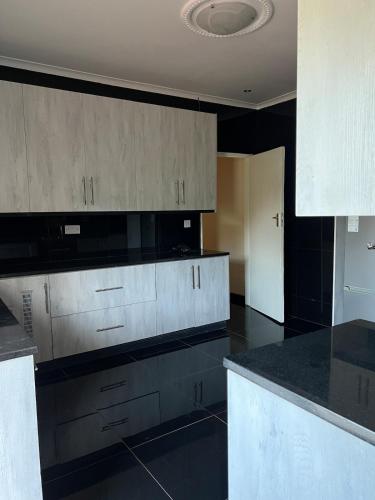 a kitchen with white cabinets and black counter tops at Indolo Home in Bulawayo
