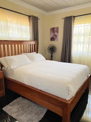 a bedroom with a large bed with white sheets and a window at Indolo Home in Bulawayo