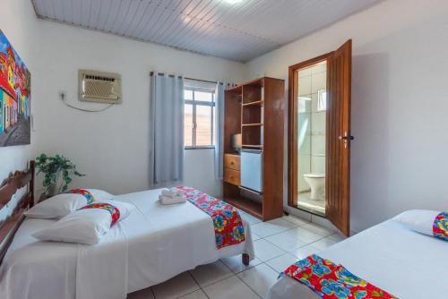 a bedroom with two beds and a bathroom at Pousada Brisa do Mar in Porto Seguro