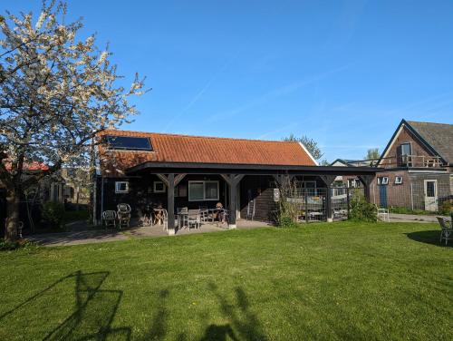 a large house with a patio and a grass yard at The Bee - Trekkershuts & Apartment in Opperdoes