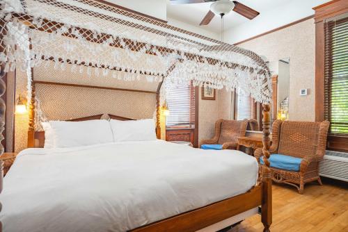a bedroom with a large bed and two chairs at Curry Mansion Inn in Key West