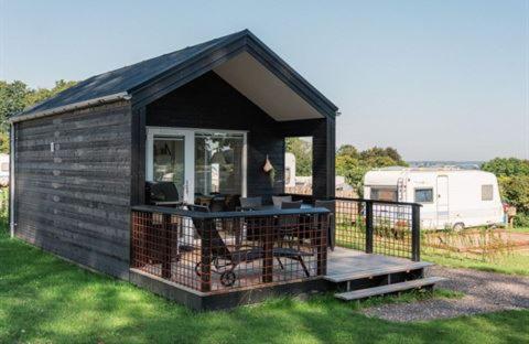 a small building with a deck with a desk at DCU-Camping Grønninghoved Strand in Sjølund