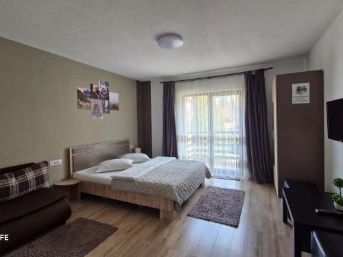 a bedroom with a bed and a couch and a window at Casa Krista in Bran