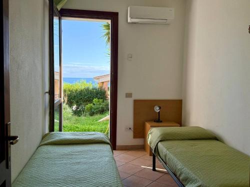 two beds in a room with a view of the ocean at Residence Il Borgo di Porto Corallo in Villaputzu
