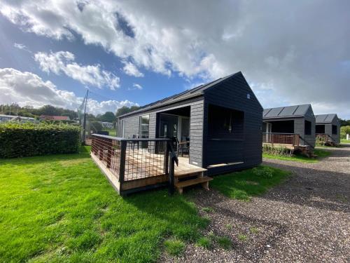 a black tiny house sitting on a grass field at DCU-Camping Grønninghoved Strand in Sjølund