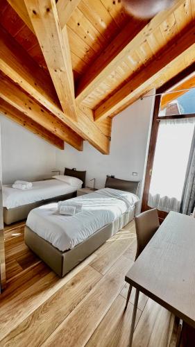 two beds in a room with wooden ceilings at Casa Stelvio in Turchi
