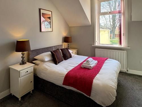 a bedroom with a bed with a red blanket and a window at Cosy and convenient Sunderland apartment in Sunderland