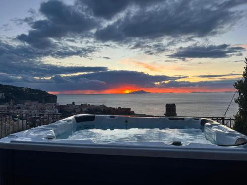a jacuzzi tub with a sunset in the background at Corte Degli Ulivi Resort in Vico Equense