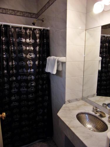 a bathroom with a sink and a shower with wine glasses at Hotel Tres Sargentos in Buenos Aires