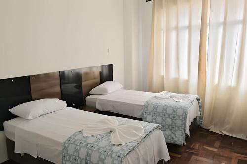 a hotel room with two beds and a window at Confortavel Apartamento na Rua das Flores in Curitiba