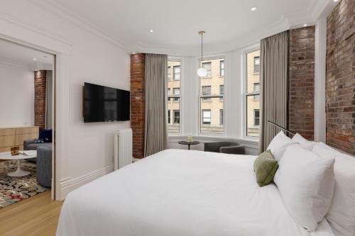 a bedroom with a white bed and a tv at Victorian Hotel in Vancouver