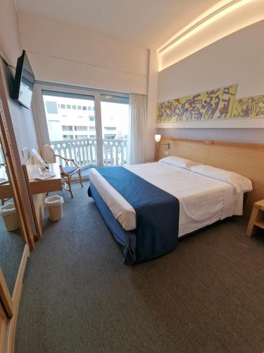 una camera d'albergo con un grande letto e un balcone di City Hotel a Senigallia
