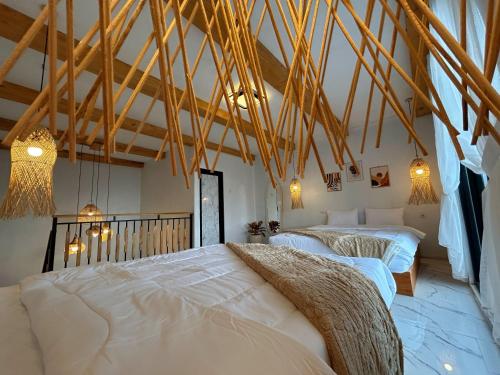 two beds in a room with wooden beams at Kizuna villa in Diyeng