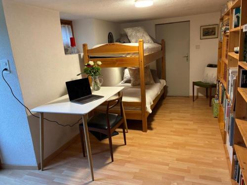 a room with a desk and a bunk bed with a laptop at Le Petit Ruisseau in Ollon