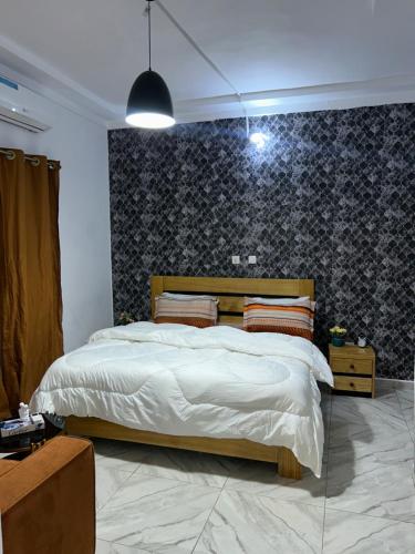 a bedroom with a large bed and a blue wall at Résidence Eden2 in San-Pédro