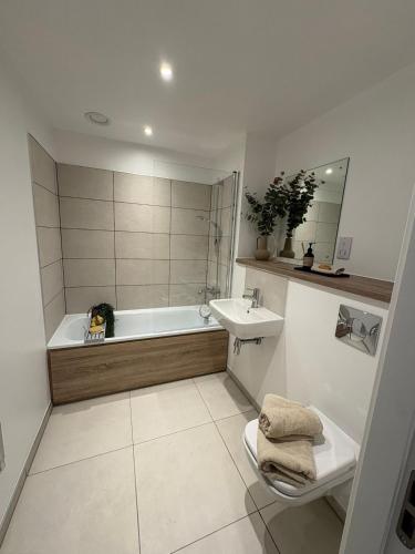 a bathroom with a tub and a toilet and a sink at Stylish 2 bedroom modern apartment central to Eccles in Manchester