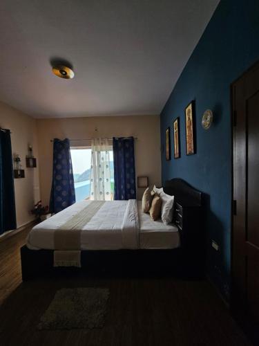 a bedroom with a bed with blue walls and a window at Kalon Elpis Villa in Ooty