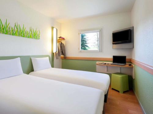 a room with two beds and a laptop on a desk at ibis Budget Pau Est in Pau