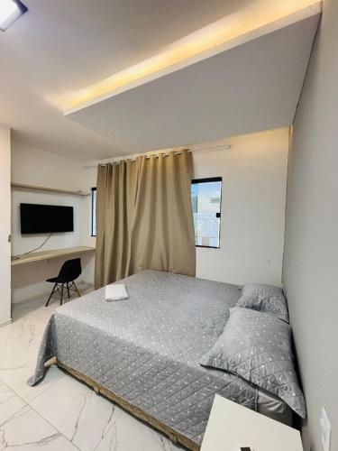 a bedroom with a bed and a desk at Flats Sucesso in Teresina