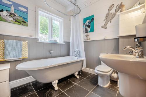 a bathroom with a tub and a sink and a toilet at 3 Bed in Little Petherick oc-maplod in Little Petherick