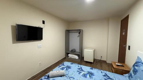 a bedroom with a bed and a flat screen tv at Caminho de Itacoatiara in Niterói