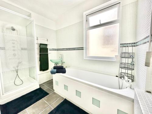 a white bathroom with a tub and a window at New Brighton Beach in Wallasey