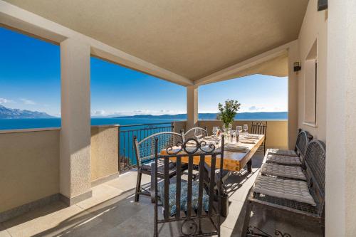 a balcony with a table and chairs and a view of the water at Mimice Hills Luxury Penthouse 229 m2, Panoramic Wrap Terrace, Jacuzzi,BBQ in Mimice