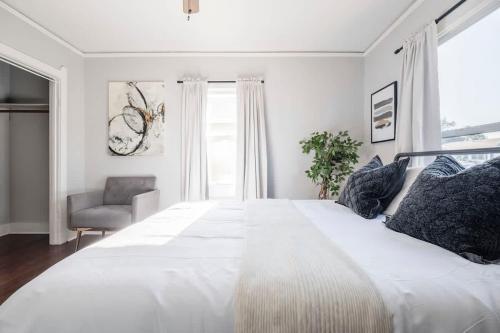 a white bedroom with a large bed and a chair at Unique Bungalow w/ hot Spa in DT in Sacramento