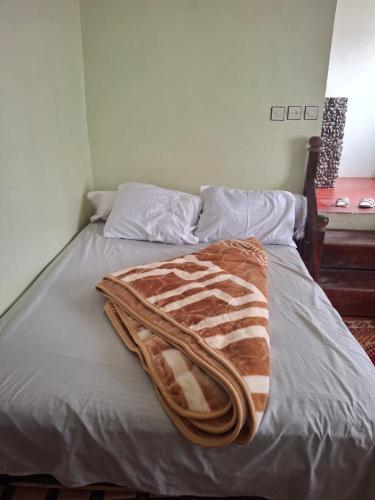 a bed with a brown and white blanket on it at Auberge Toubkal Amsouzart Aitst Idar in Tizgui