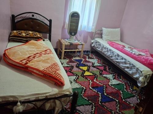 a room with two beds and a rug at Auberge Toubkal Amsouzart Aitst Idar in Tizgui