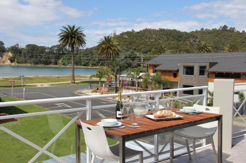 a table on a balcony with a view of a lake at Crow's Nest Apartments in Whitianga