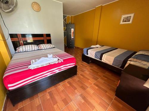 a bedroom with two beds and a clock on the wall at Hospedaje Los Pecanos in Ica