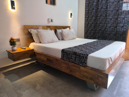 a bedroom with a large wooden bed with white sheets at OLA LUXURY HOTEL Parakou in Parakou