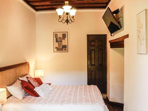 a bedroom with a bed and a chandelier at Tropicana La Catedral in Antigua Guatemala