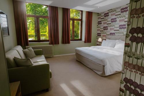a bedroom with a bed and a chair and windows at Château de Looz in Borgloon