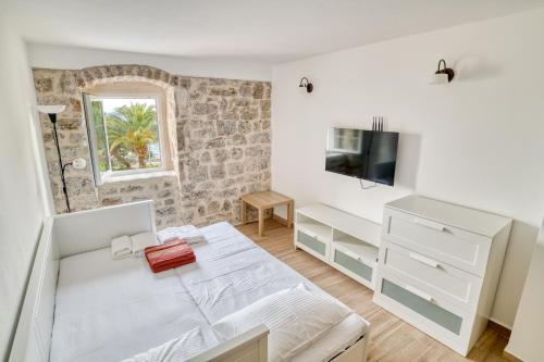 a white bedroom with a bed and a tv at SM Beach Residence in Petrovac na Moru