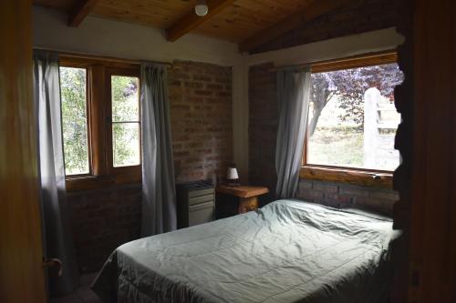 a bedroom with a bed and two windows at Camping El Paraíso in El Hoyo