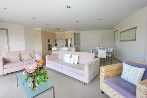 a living room with two couches and a table at Crow's Nest Apartments in Whitianga