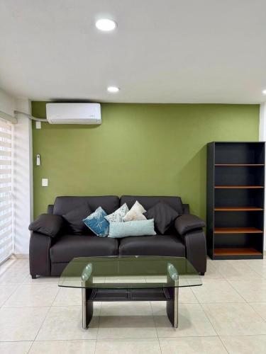 a black couch in a room with a green wall at Cozy Loft with Air Conditioning and WiFi near Poliforum Leon Gto in León
