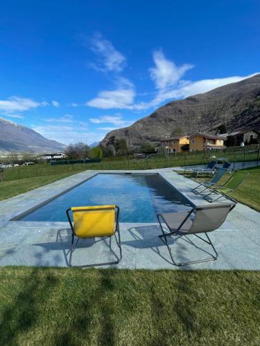 a pool with two chairs in the grass at Villa Tarca - Colico, Lake Como in Colico