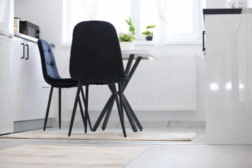 two black chairs sitting at a desk in a kitchen at White Pearl Residence in Roşu