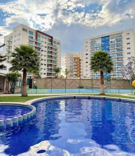 an empty swimming pool with palm trees and buildings at Cozy Loft with Air Conditioning and WiFi near Poliforum Leon Gto in León