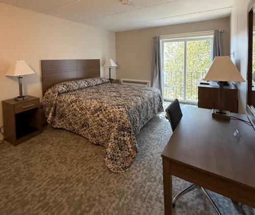 a bedroom with a bed and a desk and a window at Mushroom Cap Motel in Mesick