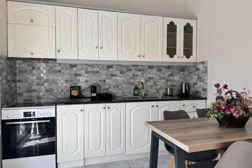 a kitchen with white cabinets and a wooden table at Airport Suites Michelle in Spata