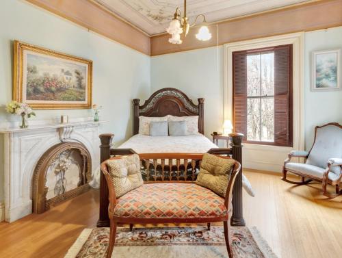 a bedroom with a bed and a chair and a fireplace at Proctor Mansion Inn in Wrentham