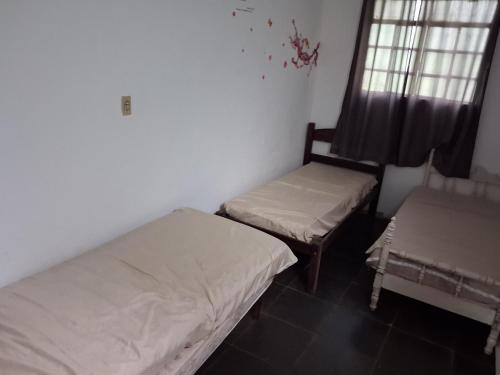 two beds in a room with a window and a bed and a chair at Sítio Limão Cravo in Areias