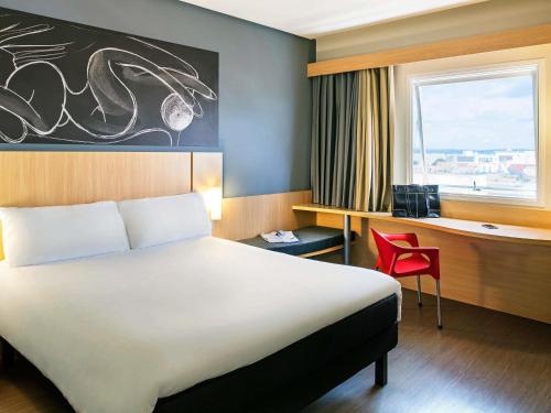 a hotel room with a bed and a desk and a window at ibis Imperatriz in Imperatriz
