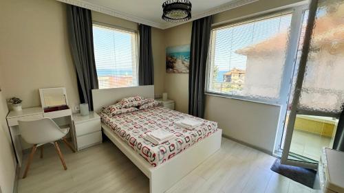 a bedroom with a bed and a desk and windows at Hedi Sozopol in Sozopol