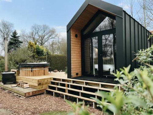 a tiny house with a black roof at Tiny Cabin met airco en privé hottub in Rutten